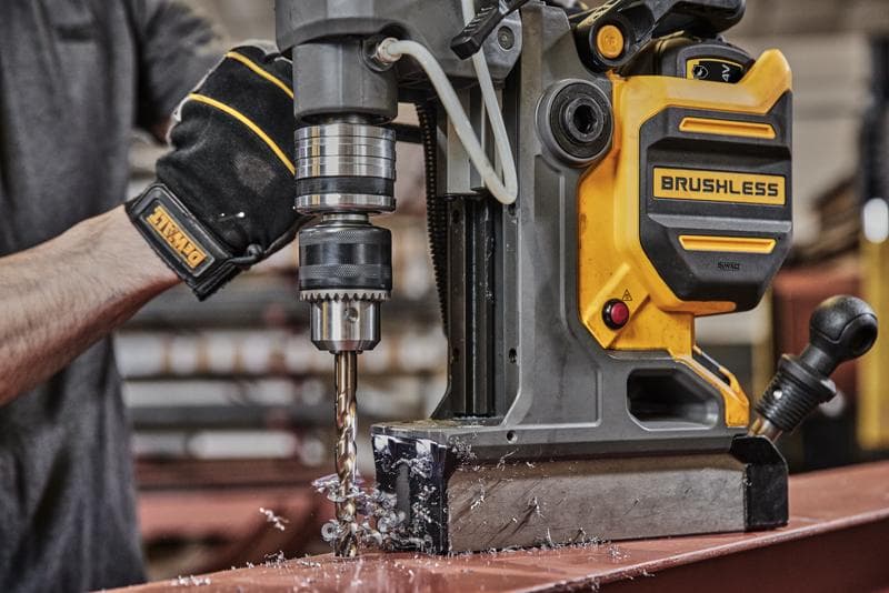 DEWALT brushless magnetic drill used on metal surface in workshop, operator wearing branded glove.